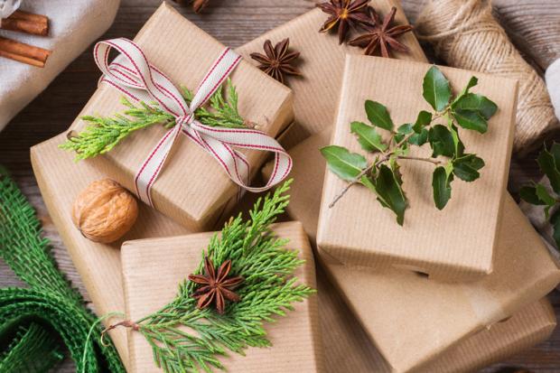 Vue sur des emballages de cadeaux en craft ou tissus avec quelques décorations végétales de Noël
