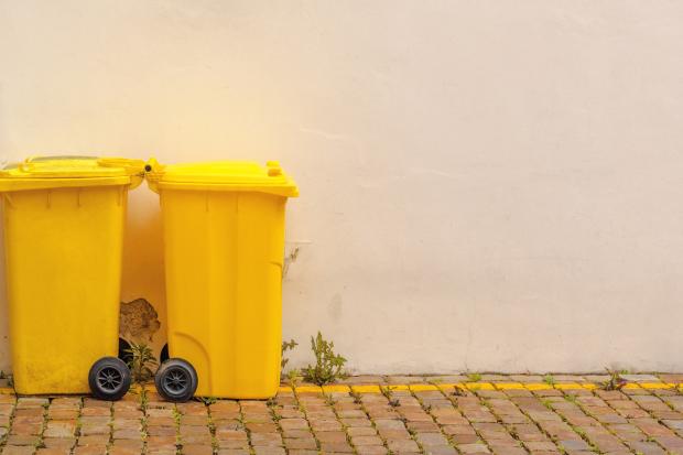Deux poubelles jaunes devant un mur